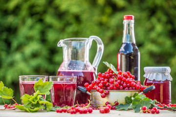A selection of redcurrant products - marmalade jam syrup must and red vine on table in garden
