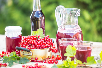 A selection of redcurrant products - marmalade jam syrup must and red vine on table in garden