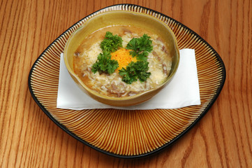 Chicken soup with noodles and vegetables in brown bowl on wooden background. Restaurant food