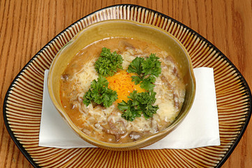 Chicken soup with noodles and vegetables in brown bowl on wooden background. Restaurant food