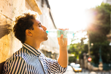 young man drinking water outside