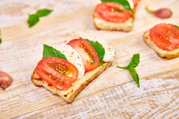 Caprese bruschetta toasts. Bruschetta with tomatoes, mozzarella cheese and basil on a rustic table. Traditional italian appetizer or snack, antipasto
