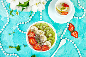 Healthy breakfast bowl smoothie with strawberry, banana, kiwi  and chia seeds on blue background. Healthy vegan food concept..