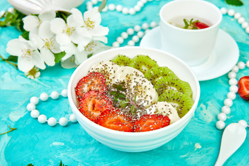 Healthy breakfast bowl smoothie with strawberry, banana, kiwi  and chia seeds on blue background. Healthy vegan food concept..