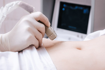 Ultrasound scanner device in the hand of a professional doctor examining his patient doing abdominal ultrasound scanning early pregnancy for a young girl - obrazy, fototapety, plakaty