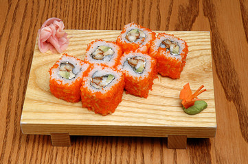 Sushi on a wooden stand, wasabi and pickled ginger. On wooden background