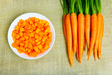 Fresh carrots with green petioles and leaves on jute background. Raw carrots full of vitamins ready...