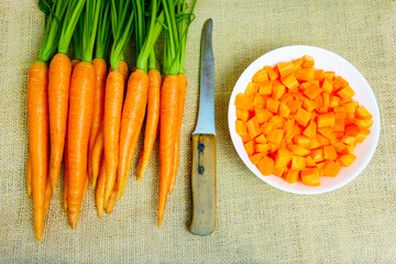 Fresh carrots with green petioles and leaves on jute background. Raw carrots full of vitamins ready...