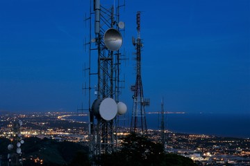 Telecommunications tower, antenna and satellite dish and coastline at night as background. Cellular...