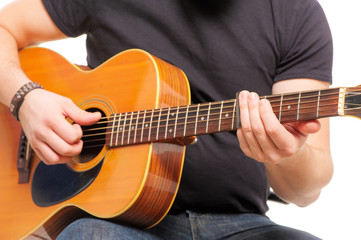 man's hands playing an acoustic guitar