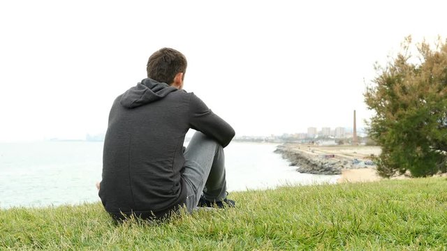 Back view portrait of a sad boy complaining looking at city outskirts