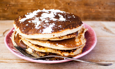 Homemade pancakes on a black cast iron skillet with berries on wooden background vintage tableware