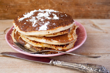 Homemade pancakes on a black cast iron skillet with berries on wooden background vintage tableware