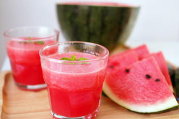 Fresh watermelon juice is in a glass and sliced watermelon on the plate.