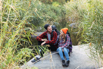 Happy young couple wearing backpacks hiking