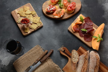 Brushetta or traditional Spanish tapas. Appetizers with Italian antipasti snacks. Variety of small sandwiches with cherry tomatoes, salmon, cream cheese. Prosciutto served with melon and basil