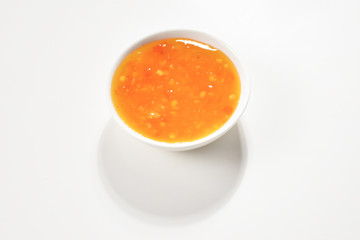 Orange sauce in white plate on white background.