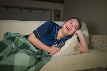 young beautiful happy and cheerful Asian Chinese woman watching TV comedy movie or hilarious show...