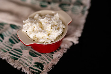 dairy product cottage cheese in brown ceramic bowl with spoon on vintage wooden table