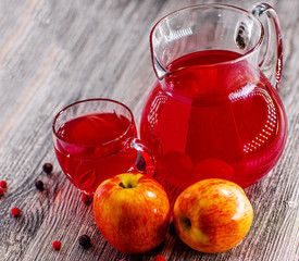 On the table there is a jar with homemade compote , two apples.