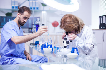 Young caucasian male scientist using a pipette analyzes a liquid to extract molecules in test tubes