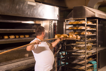 bakery worker taking out freshly baked breads