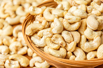 Close-up on healthy cashew nuts in a wicker bowl. Food photography. Healthy fresh cashew nuts. Minimalist photography. The Latin name of cashew is Anacardium occidentale.