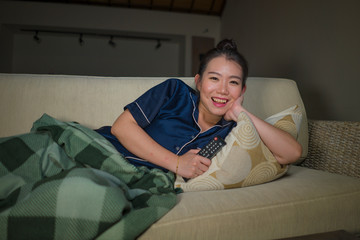 young beautiful happy and cheerful Asian Japanese woman watching TV comedy movie or hilarious show...