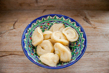 Dumplings with potato or meet served with butter or sour cream in dish on rustic wooden background