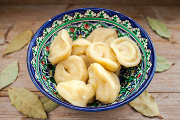 Dumplings with potato or meet served with butter or sour cream in dish on rustic wooden background