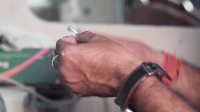 Worker in a factory for spectacles making is grinding them with the help of machine closeup