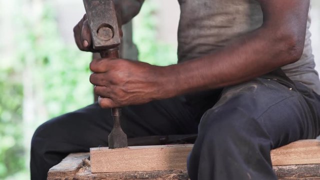 Footage of male woodworker who carves wood piece in well lit factory during the day,