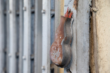 Close up of an old iron censer hanging in a grey fence