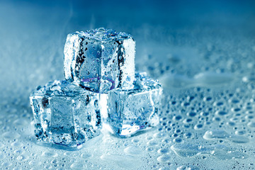 Ice cubes and water melt on cool background. Ice blocks with cold drinks or beverage.