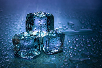 Ice cubes and water melt on cool background. Ice blocks with cold drinks or beverage.