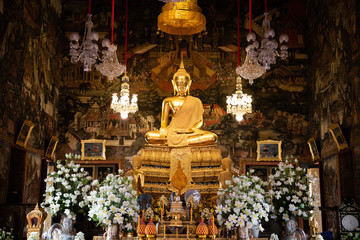 November 20th, 2018 - Bangkok (THAILAND) - Big golden Buddha surrounded by white orchids in thai temple