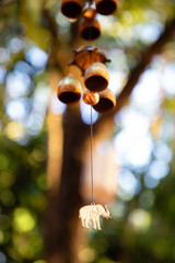Close up of hanging bells with elephant charm with green leaves in the background