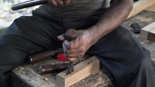Man who works as a joiner in his workshop is making holes in wooden piece of board