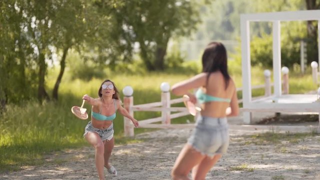 Sexy hot women in bikini and shorts playing badminton at a resort, medium shot