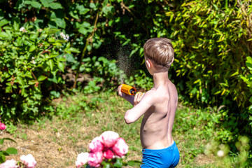 Happy little boy having fun with squirt gun in the garden