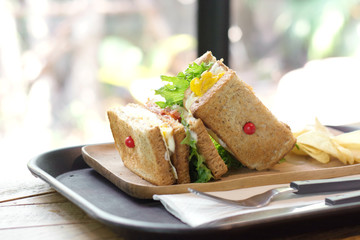 Club sandwich with bacon - chicken, fie egg, cheese, potato and lettuce on wooden tabel in cafe...