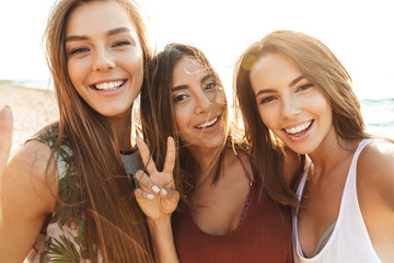 Three cheerful girls walking along the beach, having fun