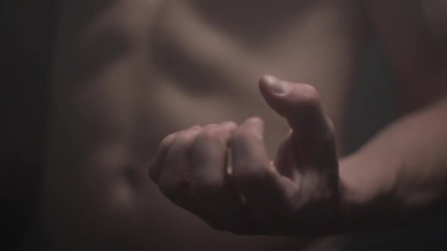 Angry man slowly clutching his hand into fist seeking revenge. Dark surroundings with smoke in the air.