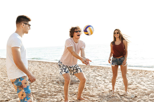 Group of cheerful friends playing volleyball