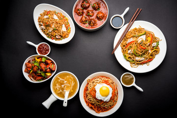 Assorted Indo chinese food in group includes non vegetarian or chicken Schezwan/Szechuan hakka noodles, fried rice, manchurian, egg american chop suey, soup with spoon and chop sticks, selective focus