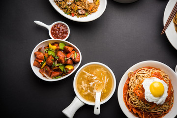 Assorted Indo chinese food in group includes non vegetarian or chicken Schezwan/Szechuan hakka noodles, fried rice, manchurian, egg american chop suey, soup with spoon and chop sticks, selective focus