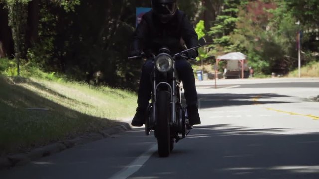 Slow Motion of Motorcyclist With Leather Jacket Riding on a Wooded Road
