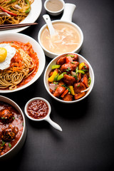 Assorted Indo chinese food in group includes non vegetarian or chicken Schezwan/Szechuan hakka noodles, fried rice, manchurian, egg american chop suey, soup with spoon and chop sticks, selective focus