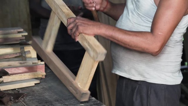 A workman using an adze to stably assemble the parts of a wooden framework