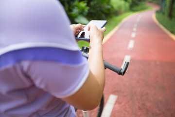 Cyclist using smart phone while riding bike on the spring forest trail